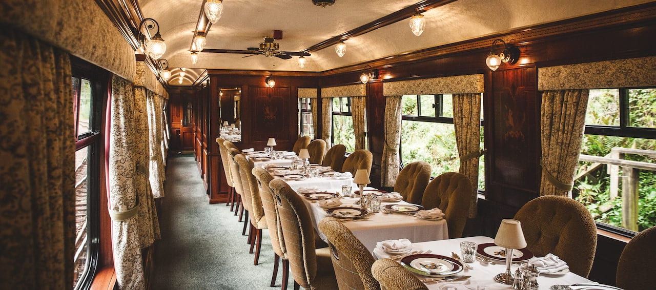Interior of the Belmond Royal Scotsman dining car, set tables with landscape views. Clans, Castles and Isles tour.