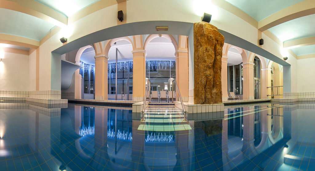 Indoor pool at RogaÅ¡ka Slatina spa, Slovenia. Arched doorways lead to an outdoor area. A rock feature is visible.